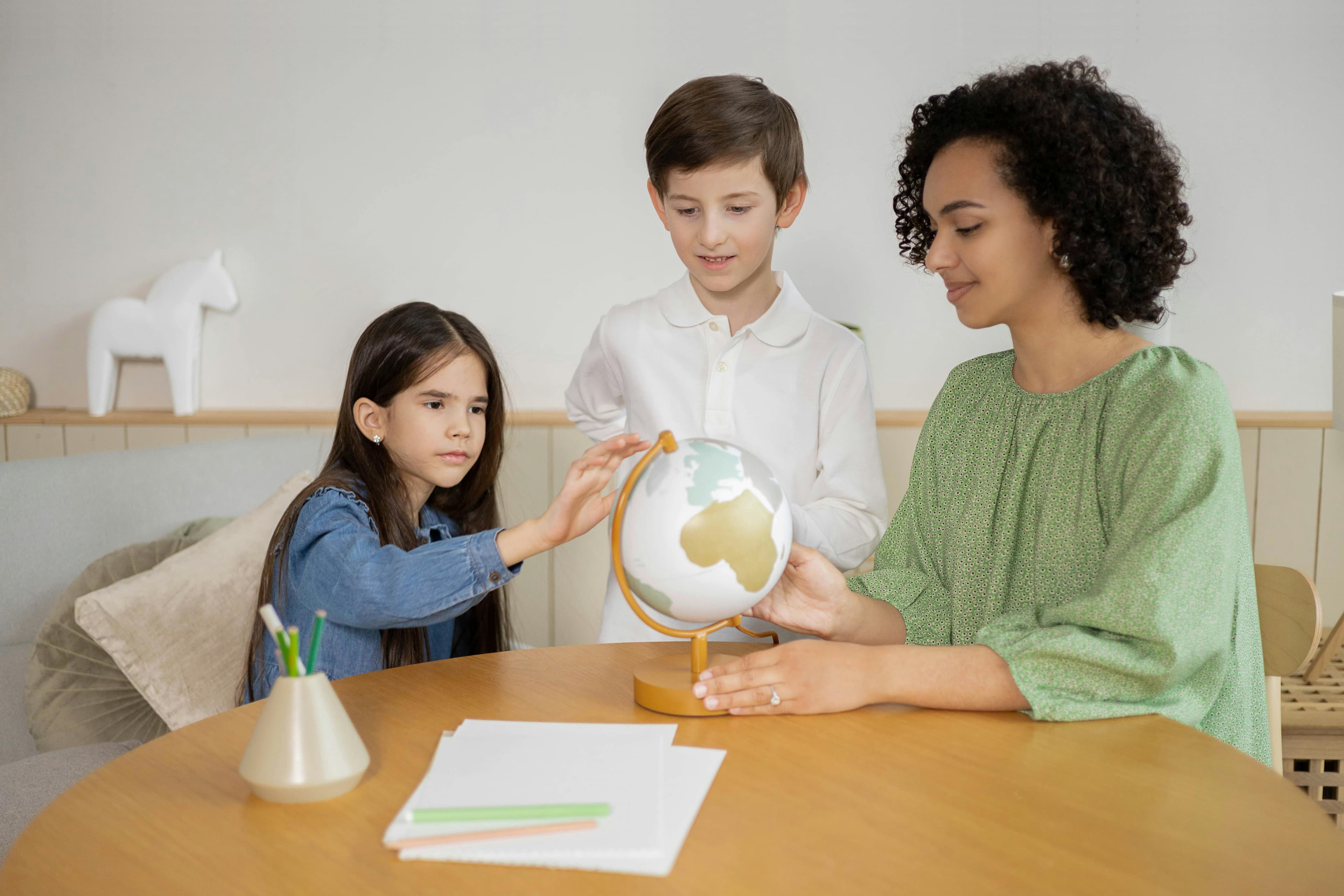 Profesora enseñando a niños con globo terráqueo